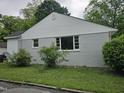 Side view of a newly renovated home with light grey paint, white trim, and green shrubbery at 605 E Montgomery St, Henderson, NC 27536