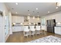 Bright kitchen with white cabinets, stainless steel appliances, a large island, and pendant lighting at 609 Ramsours Mill Dr, Holly Springs, NC 27540