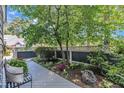 A peaceful side yard with a decorative fence, lush plants, and a seating area with chair at 7601 Wellesley N Park, Raleigh, NC 27615