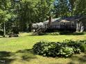 Expansive backyard featuring a manicured lawn, mulit-tiered deck, mature landscaping, and a built-in firepit at 8620 Glendale Dr, Apex, NC 27539
