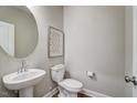 Compact powder room with pedestal sink, round mirror, and standard toilet at 9513 Wood River Dr, Zebulon, NC 27597