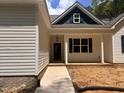 Inviting covered front porch with classic columns, a brick foundation and traditional entry door at 987 Lewis Rd, Zebulon, NC 27597
