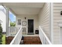 Covered front porch with brick steps, white railings, decorative chair, and black front door with sidelight at 109 Troyer Pl, Apex, NC 27502
