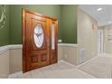 Elegant wooden double doors featuring decorative glass panels, inside a brightly lit foyer with neutral tile flooring at 174 Woodwedge Way, Sanford, NC 27332