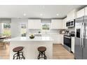 Bright kitchen with white cabinets, stainless steel appliances, center island with seating, and wood-look floors at 220 Rosewood Dr, Sanford, NC 27330