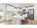 Modern kitchen featuring white cabinets, stainless steel appliances, an island with seating, and wood flooring at 220 Rosewood Dr, Sanford, NC 27330