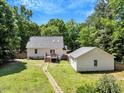 Backyard view of the house and detached structure surrounded by green grass, with a stone path at 25 Misty Way, Franklinton, NC 27525