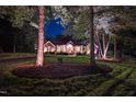 Stunning brick home at night with professional lighting highlighting the manicured lawn and mature trees at 3197 Carriage Creek Ct, Haw River, NC 27258