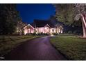 Charming brick home with a circular driveway, manicured lawn, and elegant exterior lighting at night at 3197 Carriage Creek Ct, Haw River, NC 27258