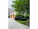Three-car garage on a white brick house with wood doors and professional landscaping at 5205 Newstead Manor Ln, Raleigh, NC 27606