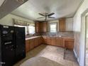 Kitchen features wooden cabinets, window above sink, and black fridge in the corner at 705 Washington St, Graham, NC 27253