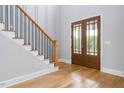 Inviting entryway features hardwood floors, a staircase with dark iron railings, and elegant glass paneled double doors at 80 Water Willow Ln, Zebulon, NC 27597