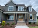 Stately home featuring a covered porch with wooden beams, brick stairs, and stylish black iron railings at 80 Water Willow Ln, Zebulon, NC 27597