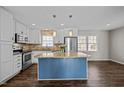 Bright kitchen features white cabinets, stainless steel appliances, a granite island, and stylish pendant lighting at 1195 Champion Dr, Cary, NC 27511