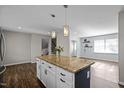 Kitchen island with granite countertop and pendant lighting, with wood floors extending into the dining area at 1195 Champion Dr, Cary, NC 27511