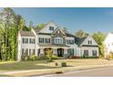 Gorgeous two-story home featuring a lush lawn, black shutters, stone accents, and covered entryway at 1475 Sierra Glen Cir, Apex, NC 27502
