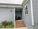 Exterior entryway with a brick staircase, covered porch, and muted blue walls at 1944 Castle Pines Dr, Raleigh, NC 27604
