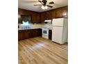 Traditional kitchen with dark wood cabinets, laminate flooring, and white appliances, offering ample storage and workspace at 225 Meadow Dr, Henderson, NC 27537