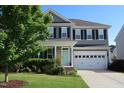 Charming two-story home with a manicured lawn, two car garage, and a welcoming light blue front door at 2309 Redbridge Ln, Apex, NC 27502