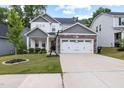Beautiful home with a well-maintained lawn and landscaping leading to a stone-accented two-car garage at 389 Whetstone Dr, Angier, NC 27501