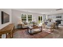 Open concept living room with large windows, a decorative rug, and seamless transition to the dining area and kitchen at 552 Stream Walk Xing, Wendell, NC 27591
