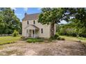 Side exterior view of the historic home with a stone chimney and mature trees at 7404 Halifax Rd, Youngsville, NC 27596