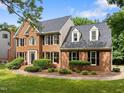 A two story home with brick facade, dormer windows, and manicured landscaping on a sunny day at 100 Silver Lining Ln, Cary, NC 27513