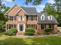 Traditional brick home featuring black shutters, dormer windows, and a professionally landscaped front yard at 100 Silver Lining Ln, Cary, NC 27513
