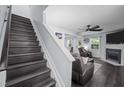 View of stairs leading to living room with wood floors, fireplace, ceiling fan, and ample natural light at 109 Gladstone Dr, Durham, NC 27703