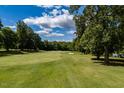 View of a lush green golf course from the property, surrounded by mature trees on a partly cloudy day at 121 Walter Hagen Dr, Mebane, NC 27302