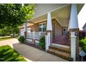 Inviting covered porch with brick steps, white railing and columns, and a cozy seating area at 1218 Crystalwater Dr, Fuquay Varina, NC 27526