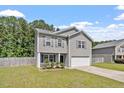 Charming two-story home featuring gray siding, a well-manicured lawn, and an attached garage at 228 Botanical Ct, Bunnlevel, NC 28323