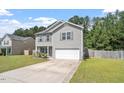 Charming two-story home featuring gray siding, a well-manicured lawn, and an attached garage at 228 Botanical Ct, Bunnlevel, NC 28323