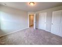 A cozy bedroom with neutral walls and carpet, featuring two doors and a ceiling light at 356 Beacon Hill Rd # 103, Lillington, NC 27546