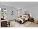 Neutral primary bedroom with a queen bed, stylish rug, and modern decor, bathed in natural light at 4009 Olde Coach Rd, Durham, NC 27707