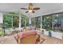 Bright sunroom with floor to ceiling windows and views of the wooded backyard and a ceiling fan at 4009 Olde Coach Rd, Durham, NC 27707