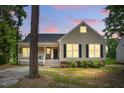 Charming single Gathering home featuring a cozy front porch with lights shining from the windows at twilight at 4905 Knightsbridge Way, Raleigh, NC 27604