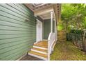 Side entrance featuring a wooden porch and stairs, leading to a white door and fenced yard at 507 N Elm St, Durham, NC 27701