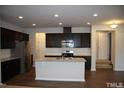 Open kitchen featuring stainless steel appliances, an island with sink, and dark cabinetry at 526 Catalina Grande Dr, Cary, NC 27519