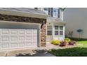 Close up of the garage and entryway with stone accents, manicured landscaping, and sidelight windows at 6 Beaver Creek Lane Ln, Durham, NC 27703