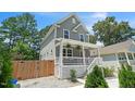 Gray two-story home with white trim, featuring a covered porch and landscaped yard with wooden fence at 647 N Hardee St, Durham, NC 27703