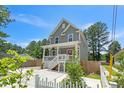 Two-story home with white-railed porch, concrete drive, and mature trees in a fenced yard at 647 N Hardee St, Durham, NC 27703