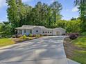 Long concrete driveway leading to a house with light blue siding and green forest backdrop at 707 Lakewood Dr, Siler City, NC 27344