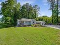 The house with light-blue siding is surrounded by lush greenery and mature trees at 707 Lakewood Dr, Siler City, NC 27344