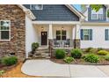 Close-up of the cozy front porch featuring rocking chairs, stone pillars, and a landscaped garden at 100 Lexington Ave, Zebulon, NC 27597