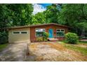 Exterior view of brick home with a blue door, surrounded by mature trees and a driveway at 112 Noble St, Chapel Hill, NC 27516