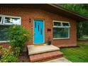Close-up of front entrance with a vibrant blue door, red brick steps, and neat landscaping at 112 Noble St, Chapel Hill, NC 27516