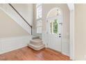 Bright foyer featuring hardwood floors, a staircase with wood trim, and a glass-paned front door at 113 Paladin Place, Cary, NC 27513