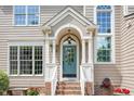 Close up of the covered front entrance with teal door, arched window, and brick stairs at 113 Paladin Place, Cary, NC 27513
