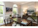 Stylish office with large windows, custom desk, artwork, and hardwood floors, perfect for working from home at 121 Flint Point Ln, Holly Springs, NC 27540
